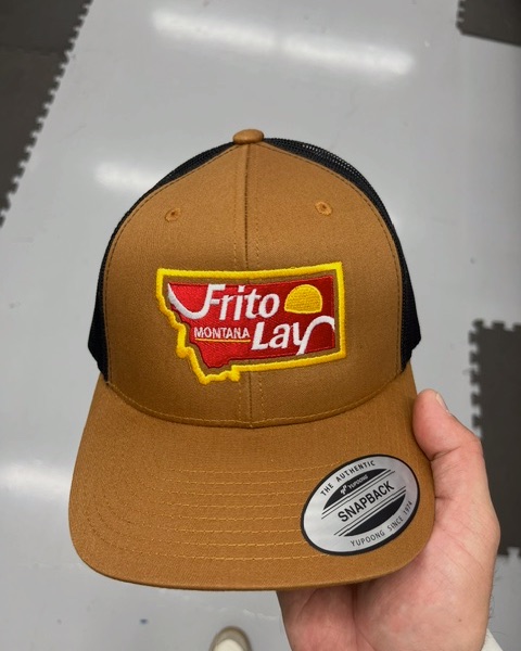 Frito-Lay Montana logo embroidered on a tan and black Yupoong snapback trucker cap